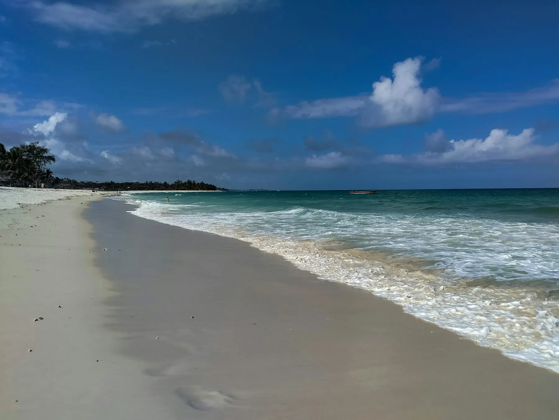 White sand beach with gentle surf under a blue sky